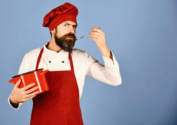 Chef-kok met rode braadpan en bestek. Koken met ernstige gezicht — Stockfoto