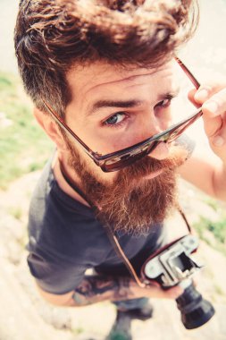 Eski moda kamera hipster katı yüz tutar. Turist fotoğrafçı kavramı. Doğa nehir ya da göl yakınındaki çekim adam. Güneş gözlüğü üzerine sakal ve bıyık koyar, arka plan su yüzeyine olan adam