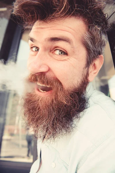 Hipster con el pelo rizado y gris en la cara alegre relajado con humo blanco que vuela por la boca. Hombre con barba y bigote humeante, fondo de mármol negro. Concepto tabaquismo y hábitos — Foto de Stock