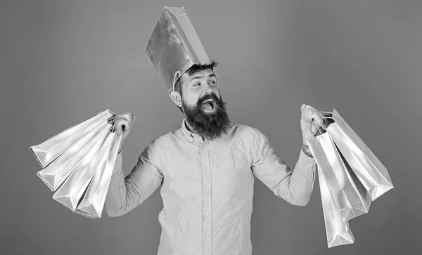 Hombre con barba elegante y rostro sonriente aislado sobre fondo azul. Hipster en camisa rosa con barba de moda haciendo compras, concepto de ventas. Feliz hombre barbudo llevando bolsas de papel y gritando de alegría —  Fotos de Stock