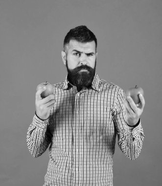 Sakallı adam kırmızı ve yeşil elma tutuyor.