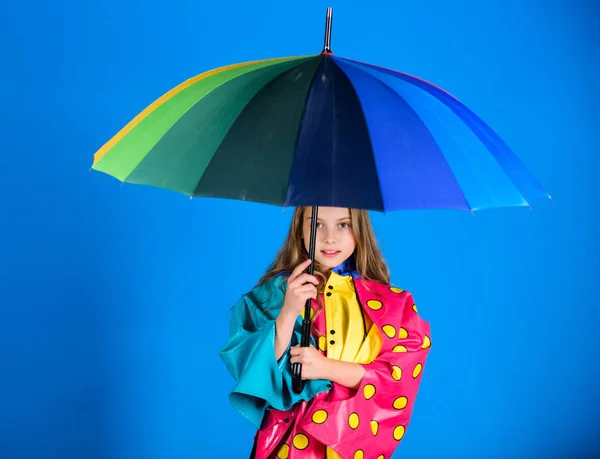Vodotěsné příslušenství vyrábět. Užijte si deštivé počasí vlastního oblečení. Vodotěsné příslušenství aby deštivý den, veselá a příjemná. Šťastné dítě dívka drží Barevný deštník opotřebení Nepromokavý plášť — Stock fotografie