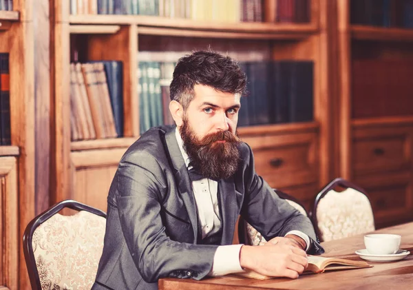 L'uomo barbuto si siede in interni classici e legge . — Foto Stock