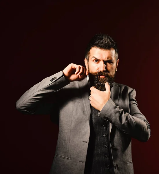 Man with long beard holds steel scissors. Barbershop advertising