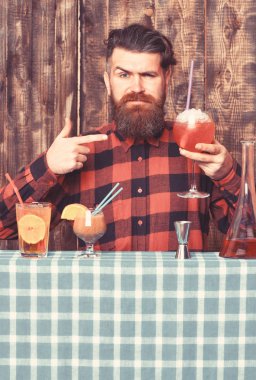Adam ahşap arkaplanda kokteyli işaret ediyor..