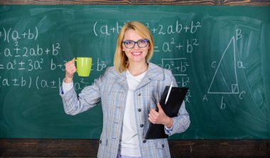 Rahat ve olumlu için zaman bulmak. Öğretmen çay veya kahve içmek ve pozitif ol. Olumlu tutum çalışmaya devam et. Kadın çay Kupası ve belge klasörü kara tahta arka plan ile. Dinlenmek için zaman