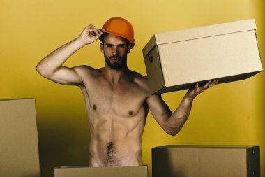 Cinsellik ve bina konsepti: seksi gövdeli adam karton kutu tutuyor.