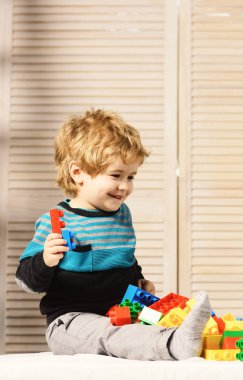 Çocuk, tahta duvar arkasında lego oynuyor..