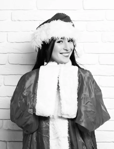 Довольно симпатичная сексуальная девушка Санта или улыбающаяся брюнетка в новогоднем красном свитере и рождественской шляпе или шапке на белой кирпичной стене backgroun — стоковое фото