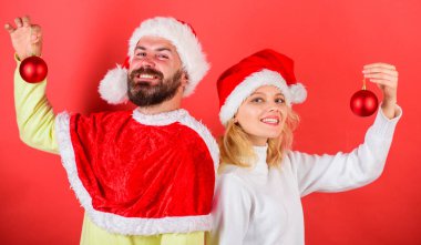 Çift Noel Noel Baba kostüm süsleme topu tutun. Noel kutlamaları kavramı. Christmas dekorasyon gelenek. Arka arkaya Noel bekleyen kadın ve sakallı adam Noel Baba şapkası stand