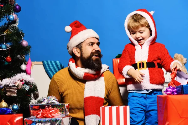 Weihnachtsmann und kleiner Helfer inmitten von Geschenkboxen am Weihnachtsbaum. — Stockfoto