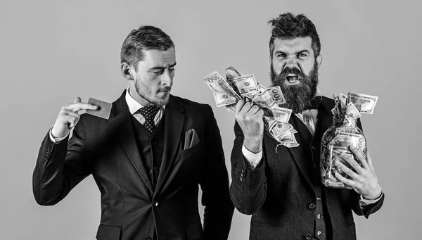 Loan and banking concept. Men in suit, businessmen with jar full of cash and credit card, pink background. Mature man on shouting face got loan, modern guy holds credit card, electronic money