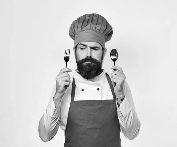 Homme avec barbe tient fourchette et cuillère sur fond blanc. — Photo