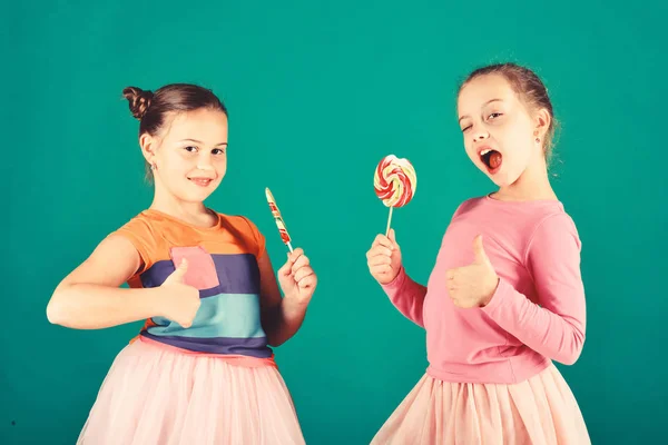 Las niñas comen grandes caramelos dulces de colores. Niños con caras felices — Foto de Stock