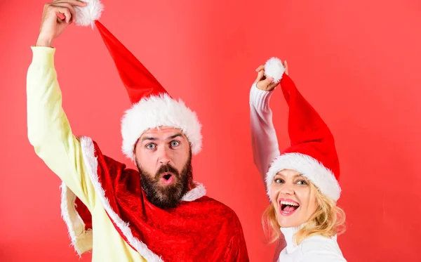 Homme avec barbe et femme en chapeau de Père Noël avec fond rouge pompon. Couple visage joyeux célébrer Noël. Couple célébrer Noël vacances d'hiver fête. Mascarade de Noël ou concept de carnaval — Photo