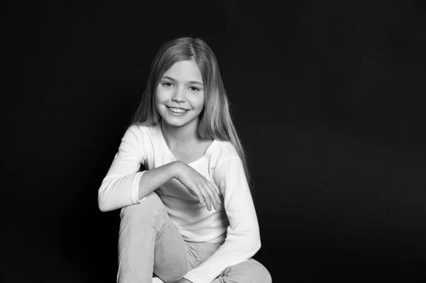 Criança feliz com penteado de moda no fundo preto. Menina sorrir com cabelo loiro longo. Menina beleza sorrindo com olhar adorável. Salão de beleza. Mantenha a calma e faça o seu cabelo — Fotografia de Stock