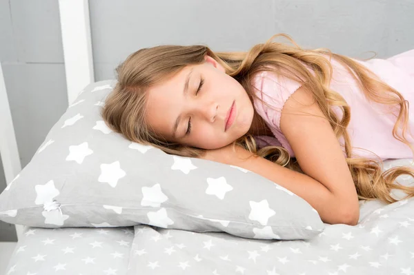 Dicas de sono saudável. Menina dormir em pouco travesseiro roupa de cama fundo. Miúdo longo cabelo encaracolado adormecer travesseiro perto. Escolha o travesseiro adequado para relaxar. Travesseiro bonito e roupas de cama para quarto infantil — Fotografia de Stock