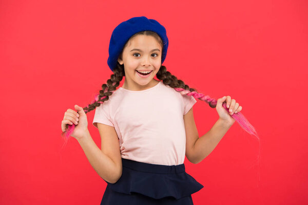 Маленькая милая девочка, улыбающееся лицо, позирующее на красном фоне. Как носить французский берет. Вдохновение от берета. Как носить береты, как девушки из моды. Модный беретный аксессуар для женщин
