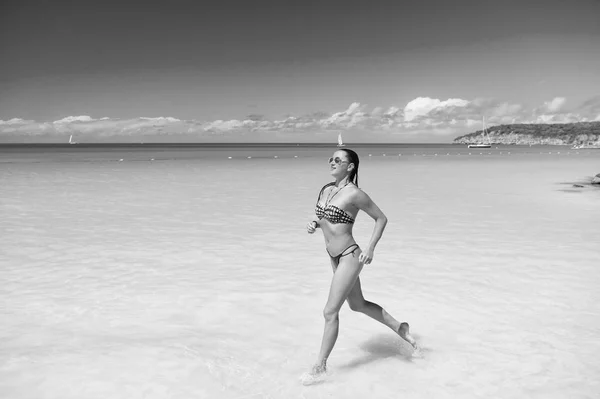 Girl swimwear bikini run wave azure ocean beach. Vacation luxury tropic ocean beach resort. Run through magical turquoise lagoon. Woman sexy body relax ocean beach Antigua. Refreshed and sun tanned