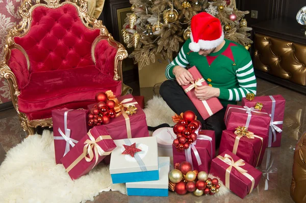 Estou a gostar do Natal. Um homem de chapéu de Pai Natal tem prendas de Natal. O tipo está a celebrar o Natal em casa. Entrega Presentes de Natal. Homem feliz com caixas de presente de Natal. Entre no espírito da temporada — Fotografia de Stock