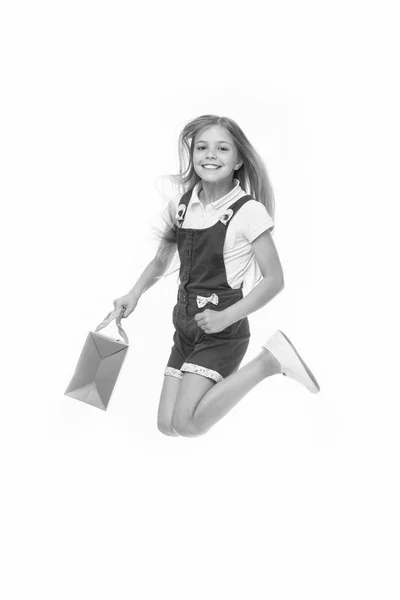 Feliz salto de niño con bolsa aislada en blanco. Una pequeña sonrisa adicta a las compras con una bolsa de papel en movimiento. Chica comprador celebrar la compra. Compras y venta. Viernes Negro —  Fotos de Stock