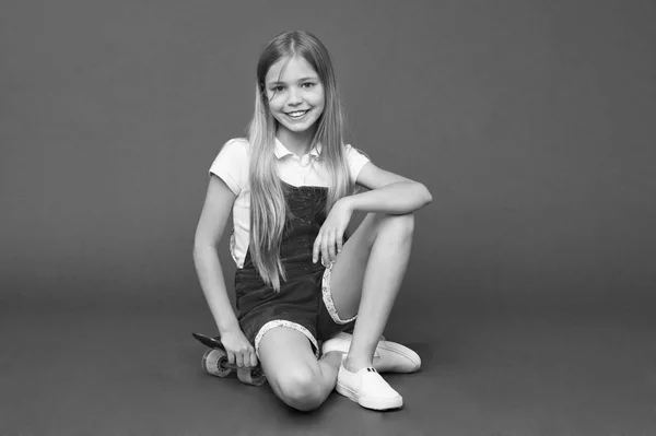 Detente y relájate. Niña relajarse se sienta tablero de peniques. Pasatiempo juvenil moderno. Chica cara feliz sentado en penny board fondo violeta. Originalmente diseñado como niñas monopatín. Feliz infancia. — Foto de Stock