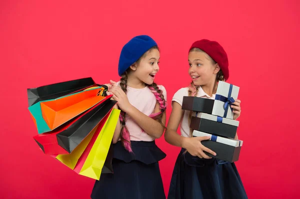 買い物中毒の概念。最高の友人と楽しみになるショッピングします。子供は赤い背景を買い物で満足。ショッピング モールの服と取りつかれています。子供たちのかわいい女子学生が束ショッピング袋を保持します。 — ストック写真
