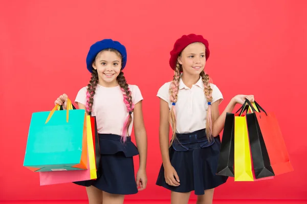 Crianças alunos satisfeitos por compras fundo vermelho. Obcecado com compras e centros comerciais. Conceito Shopaholic. Sinais de que você é viciado em compras. Crianças bonito alunas segurar monte sacos de compras — Fotografia de Stock