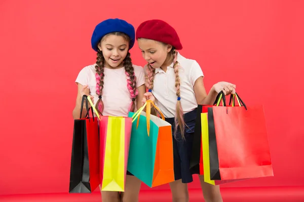 Концепция шопоголика. Знаки пристрастия к шоппингу. Дети милые школьницы держат кучу сумок для покупок. Дети-школьники довольны покупками на красном фоне. Одержимый магазинами и магазинами одежды — стоковое фото
