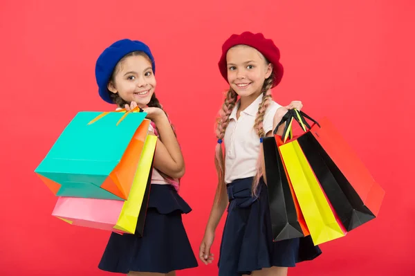 购物成为乐趣与最好的朋友。孩子们可爱的女学生拿着一堆购物袋。孩子们满意的购物红色背景。痴迷于购物和服装商场。购物狂的概念 — 图库照片