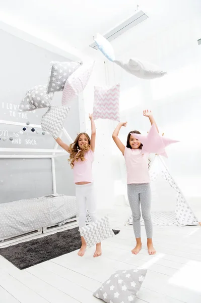 Hora de la noche por diversión. Ideas para fiestas de pijamas. Las hermanas juegan a la fiesta de almohadas. Fiesta de pijama de pelea de almohadas. Chicas felices mejores amigos o hermanos en lindo pijama con estilo con almohadas fiesta de pijamas — Foto de Stock