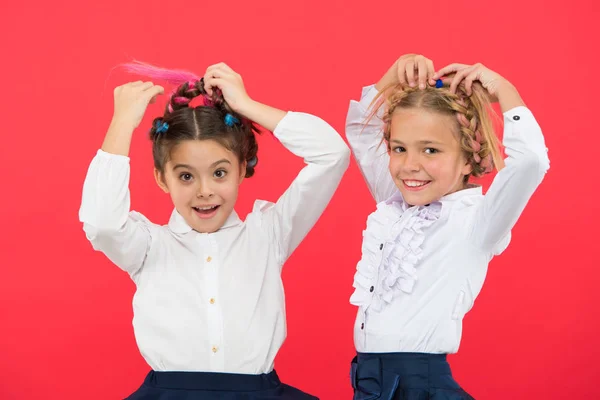 Mantenga el cabello trenzado para un aspecto ordenado. Los niños juegan con el pelo largo trenzado. Peluquería. Peinados que se adapte al estilo formal de la escuela. Peinado apropiado. Niñas trenzas largas fondo rojo — Foto de Stock