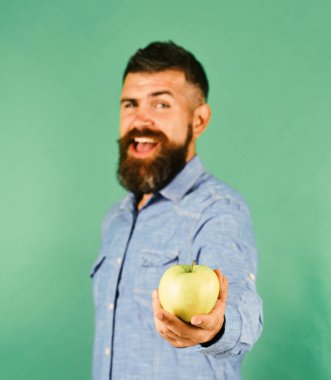 Sakallı adam yeşil arka planda yeşil meyveler tutuyor.