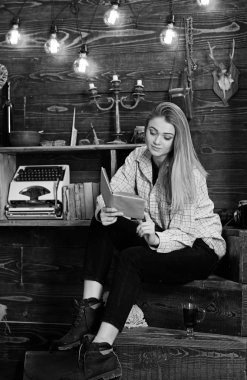 Kız öğrenci çalışma kitabı içinde hakem ev ile. Bayan kareli giysiler içinde sakin yüzünde sevimli ve rahat görünüyor. Çalışma kavramı. Ahşap vintage iç kitap ile gündelik kıyafeti kız oturur