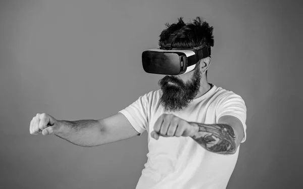Konzept virtueller Fahrstunden. Hipster auf selbstbewusstem Gesichtsfahrrad in virtueller Realität mit modernem digitalen Gadget. Mann mit Bart und Brille fährt Motorrad, roter Hintergrund — Stockfoto