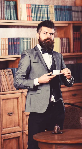 Lawyer stands in luxury interior with cup of tea or coffee.