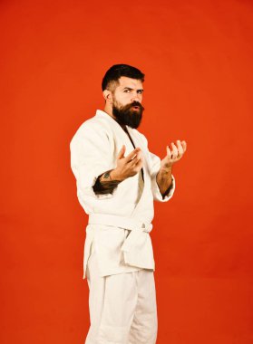 Kırmızı arka planda beyaz kimonolu sakallı adam.