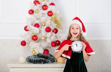 Kız çocuk santa şapka kostüm tutun saat zaman yeni yıla sayımı mutlu yüz ifadesi heyecanlı. Son dakika gece yarısına kadar. Son dakika yılbaşı planı. Neşeli Noel kavramı. New year sayım