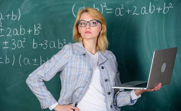 Afstand onderwijs concept. Vrouw leraar slijtage brillen houdt laptop surfen op internet. School innovatieconcept. De elegante dame van de leraar met moderne laptop surfen internet schoolbord achtergrond — Stockfoto