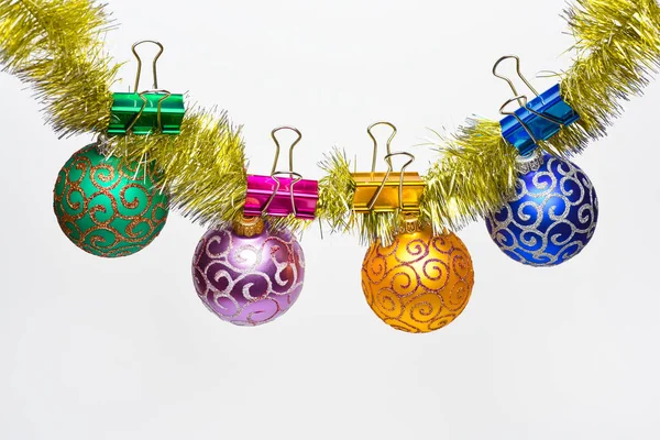 Концепция рождественских украшений. Яйца с блестящими орнаментами висят на мерцающей золотой мишуре. Тинзель с приколотыми рождественскими шарами или орнаментами, белый фон, пространство для копирования — стоковое фото