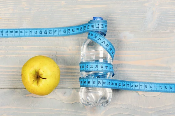 Water, measuring tape and apple, top view