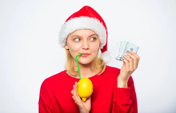 柠檬钱的概念。女孩圣诞老人帽子喝果汁柠檬, 而持有桩钱。用新鲜的柠檬水赚钱。圣诞节利润概念。财富和丰富的象征。富有的女孩与柠檬和金钱 — 图库照片
