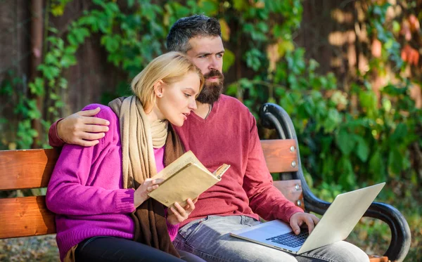 Couple with book and laptop search information. Share or exchange information knowledge. Man and woman use different information storage. Couple spend leisure reading. Information source concept