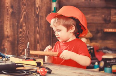 Ahşap Pano çivi çekiç çocuk evlat. Kavram handcrafting. Meşgul yüz oyunlarında evde atölye üzerinde yürümeye başlayan çocuk. Çocuk kask Oluşturucu veya repairer, onarımı veya handcrafting olarak oynayan sevimli içinde