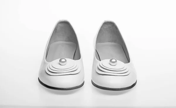 Schoenen gemaakt van wit leder op witte achtergrond, geïsoleerd. Schoeisel voor vrouwen op platte zool met parel parel als decor. Minimalisme concept. Paar modieuze comfortabele ballerina's schoenen — Stockfoto