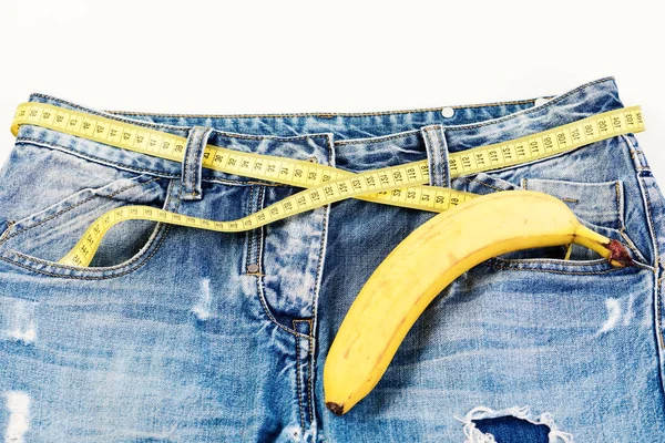 Calça jeans com banana imitando genitais masculinos em fundo branco — Fotografia de Stock