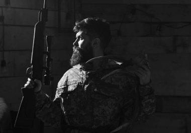 Avcı kavramı. Portre onun kupa ile sakallı modern avcı tüfeği tutar. Sakallı kamuflaj elbiseler, koyu arka plan giyer. Avcı silah, acımasız ışıklı karanlıkta, kopya alanı