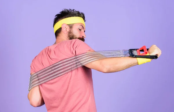 El deportista usa ropa retro entrenando fondo violeta. Instructor de deporte atleta. Entrenamiento de deportistas con expansor de pecho. Hombre atleta barbudo haciendo ejercicio con equipo expansor. Concepto deportivo de atletismo — Foto de Stock