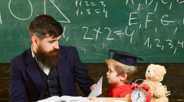 Sakal, evlat, çocuk çocuk öğretmen öğretir Peder. Evlat çalışmalar öğretmen, defterini, saat, oyuncak yakın ile. Öğretmen ve öğrenci kolej, kara tahta arka plan içinde. Eğitim çocuk kavramı