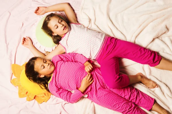 Los niños con caras somnolientas yacen cerca sobre un fondo de manta rosa —  Fotos de Stock